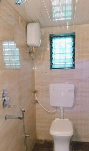 a bathroom with a toilet and a shower with a window at Ivy Little Door Cottage, Compact AC 3 BHK with Pool, Lonavala in Lonavala +15 photos