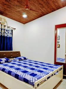 a bedroom with a bed with a blue and white comforter at Ivy Little Door Cottage, Compact AC 3 BHK with Pool, Lonavala in Lonavala