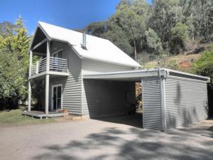 a building with a garage with a balcony at Captain Moonlight Cottage in Mount Beauty