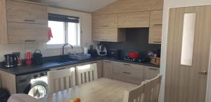 una cocina con armarios de madera, mesa y fregadero en Boulevard, en Selsey