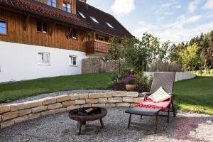 a patio with two chairs and a fire pit and a house at Naturidyl Schneckenbuch in Weißensberg +7 photos
