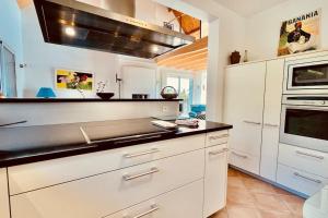 a kitchen with white cabinets and a stove top oven at Les agapanthes - vue mer in Roscanvel
