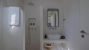 a white bathroom with a sink and a mirror at Kalami Suites in Livadi