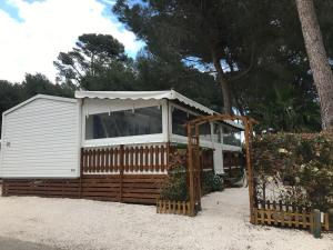 een wit huis met een hek en een boom bij Mobilhome 6 personnes en bord de mer in Hyères