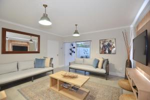ein Wohnzimmer mit 2 Sofas und einem TV in der Unterkunft Maki-Saki Boutique Self-Catering Accommodation in Yzerfontein