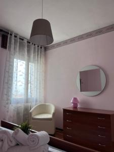 1 dormitorio con espejo, silla y tocador en Appartamenti Ziliotto en Borso del Grappa