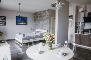 salon z łóżkiem i stołem z kwiatami w obiekcie Łódź Fabryczna Apartament w Łodzi