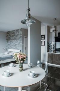 biały stół z krzesłami i wazonem z kwiatami na nim w obiekcie Łódź Fabryczna Apartament w Łodzi