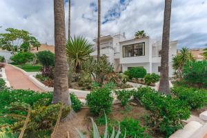 a house with palm trees in front of a yard at Two bedroom apartment near the ocean in Playa de las Americas