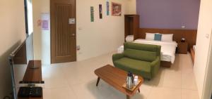 a hotel room with a green chair and a bed at Bear Baby Homestay in Jinning