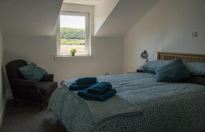 a bedroom with a bed with blue pillows and a window at Taobh na Mara in Kensaleyre