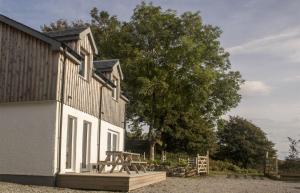 a building with a wooden deck next to a tree at Taobh na Mara in Kensaleyre