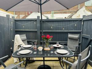 a black table with a vase of flowers on a patio at Sea La Vie - central home w BBQ, Sunny Patio, Luxurious interiors and seconds from Beach in Kent
