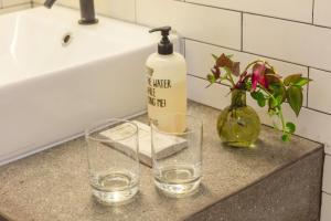 a bathroom counter with two glasses and a bottle of soap at Pico do Refúgio - Casas de Campo in Ribeira Grande