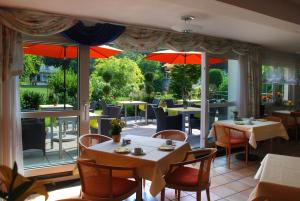 a restaurant with tables and chairs and umbrellas at Hotel Im Winkel Appartements und Zimmer in Langenargen