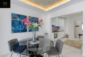 un comedor con una mesa de cristal con un jarrón de flores en Stylish 1BR Penthouse w Panoramic Views & BBQ by 360 Estates, en Il-Gżira