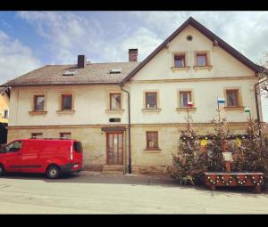 un furgone rosso parcheggiato di fronte a una casa. di Monteurwohnung nähe Bayreuth, Parken frei, Wifi, Küche a Mistelgau