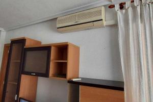 Zimmer mit einem TV und einer Klimaanlage an der Wand in der Unterkunft Apartamento Maria Salamanca 8 in Santa Pola
