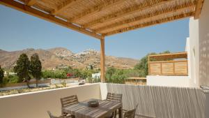 a patio with a table and chairs and mountains at Kalami Suites in Livadi