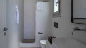 a white bathroom with a toilet and a shower at Kalami Suites in Livadi