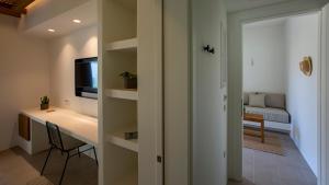 a room with a desk and a table with a television at Kalami Suites in Livadi