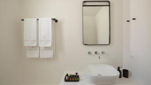 a white bathroom with a sink and a mirror at Kalami Suites in Livadi
