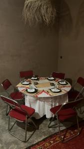 einem Tisch mit roten Stühlen und einem Tisch mit Tellern darauf in der Unterkunft Dar Talmoudi in Tagounite