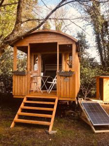 una pequeña casa de madera con porche y parrilla en Relax in the unique and cosy Off-grid Eco Shepherd's hut Between Heaven and Earth, en Mountshannon