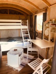 MountshannonにあるRelax in the unique and cosy Off-grid Eco Shepherd's hut Between Heaven and Earthの二段ベッド、テーブル、デスクが備わる客室です。