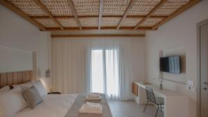 a bedroom with a bed and a desk and a television at Kalami Suites in Livadi