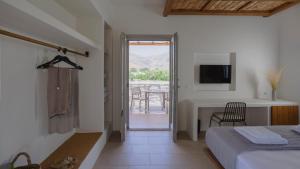 a bedroom with a bed and a desk and a television at Kalami Suites in Livadi