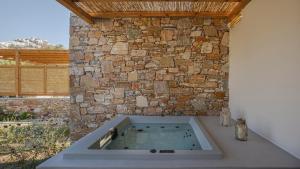 a bath tub in front of a stone wall at Kalami Suites in Livadi