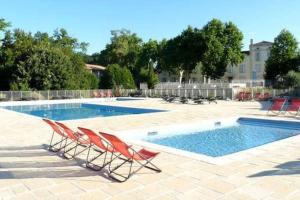 a swimming pool with two chairs and a swimming pool at Le soleil d Eugènie appartement dans résidence avec Piscine commune près de Carcassonne in Olonzac