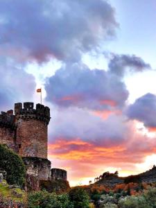 een kasteel met een vlag erop bij zonsondergang bij Hostal Villa el Colmenar in Mombeltrán