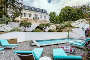 una piscina con sedie e ombrelloni di fronte a un edificio di Manoir d'Amaury - Chambres d'hôtes a Gréoux-les-Bains