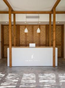 a white reception desk in a room with wood columns at Kalami Suites in Livadi