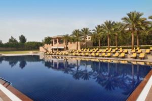 a swimming pool with lounge chairs and palm trees at Marriott Mena House, Cairo in Cairo