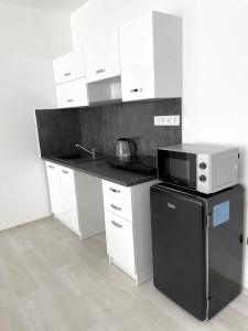 a kitchen with white cabinets and a black microwave at MG Apartments Štúrovo in Štúrovo