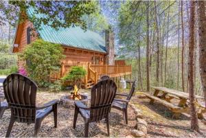 two chairs and a fire pit in front of a cabin at Lazy Bear Cabin in Sevierville