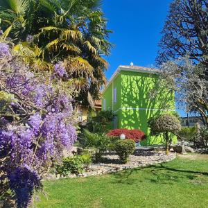 a garden with purple flowers and a green building at B&B Le Palme in Appiano Gentile