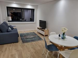 - un salon avec une table et une télévision dans l'établissement Blue Beach Apartment - Caminhos de Santiago-Airport, à Praia de Angeiras