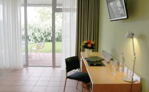 Habitación con escritorio, sillas y puerta corredera de cristal. en Seminarhotel in der Manfred-Sauer-Stiftung, en Lobbach