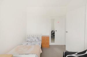 una camera bianca con letto e specchio di The Lovely Room a Londra