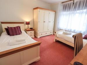 a bedroom with a bed and a dresser and a bed sidx sidx sidx sidx at Gildabrook Cottage in Bowness-on-Windermere