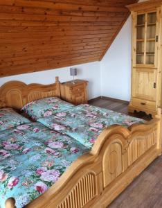 1 Schlafzimmer mit einem Holzbett mit einer Blumenbettdecke in der Unterkunft FERIENHAUS ZUM HOLZMICHEL in Thale