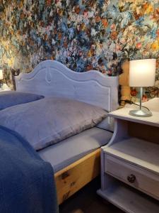 ein Schlafzimmer mit einem weißen Bett mit Blumentapete in der Unterkunft FERIENHAUS ZUM HOLZMICHEL in Thale