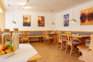 un restaurante con mesas de madera, sillas y pinturas en Hotel am Schwanberg en Rödelsee