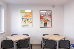 dos mesas y sillas en una habitación con carteles en la pared en Dom Studencki Komenik, en Leszno