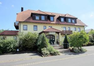 una gran casa amarilla con techo rojo en Hotel am Schwanberg en Rödelsee