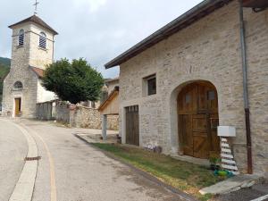 an old stone building with a wooden door and a church at La Vie du Bief in Bolozon